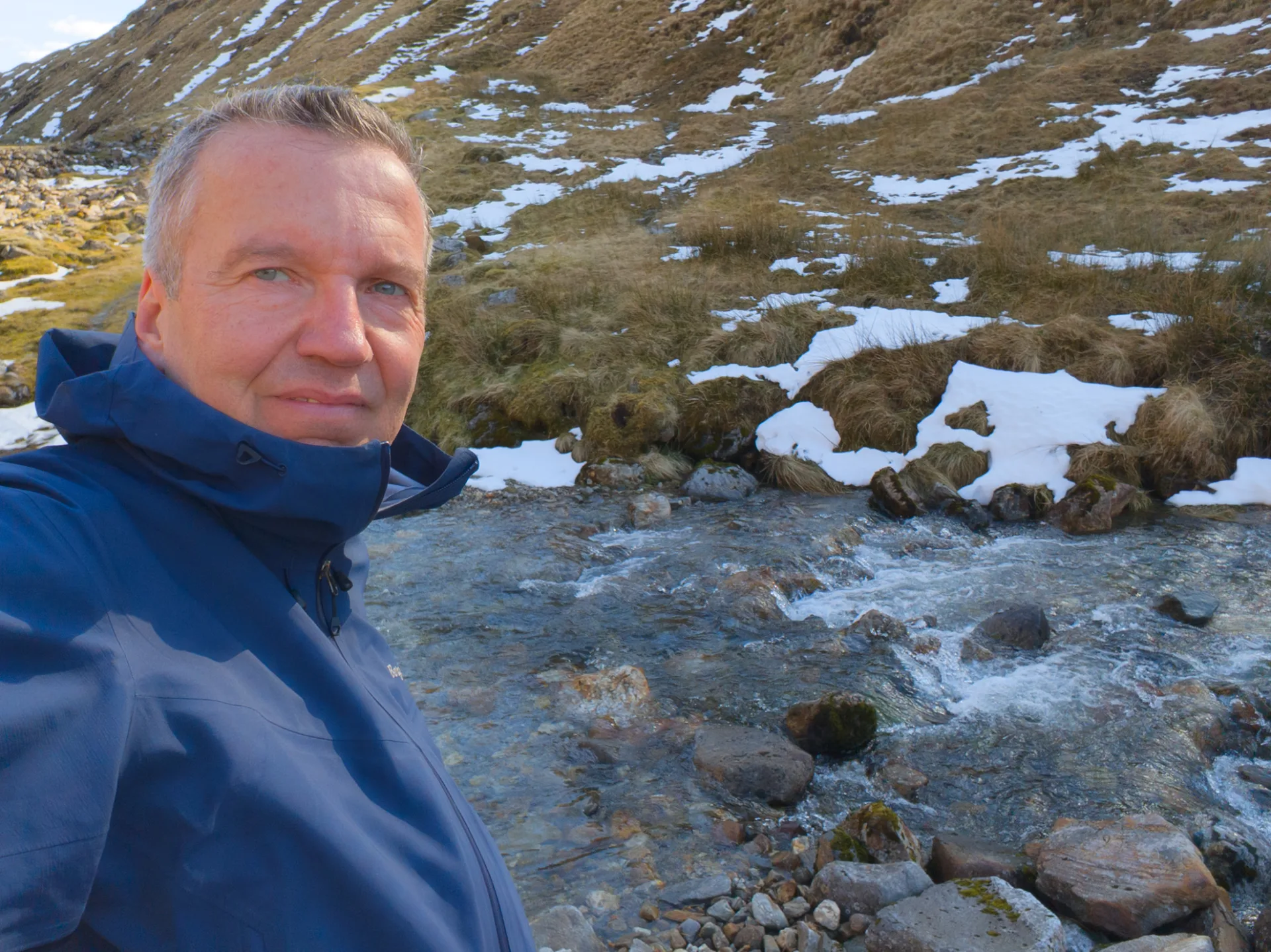 Kurze Pause am Bach — Schnee am Hang oberhalb