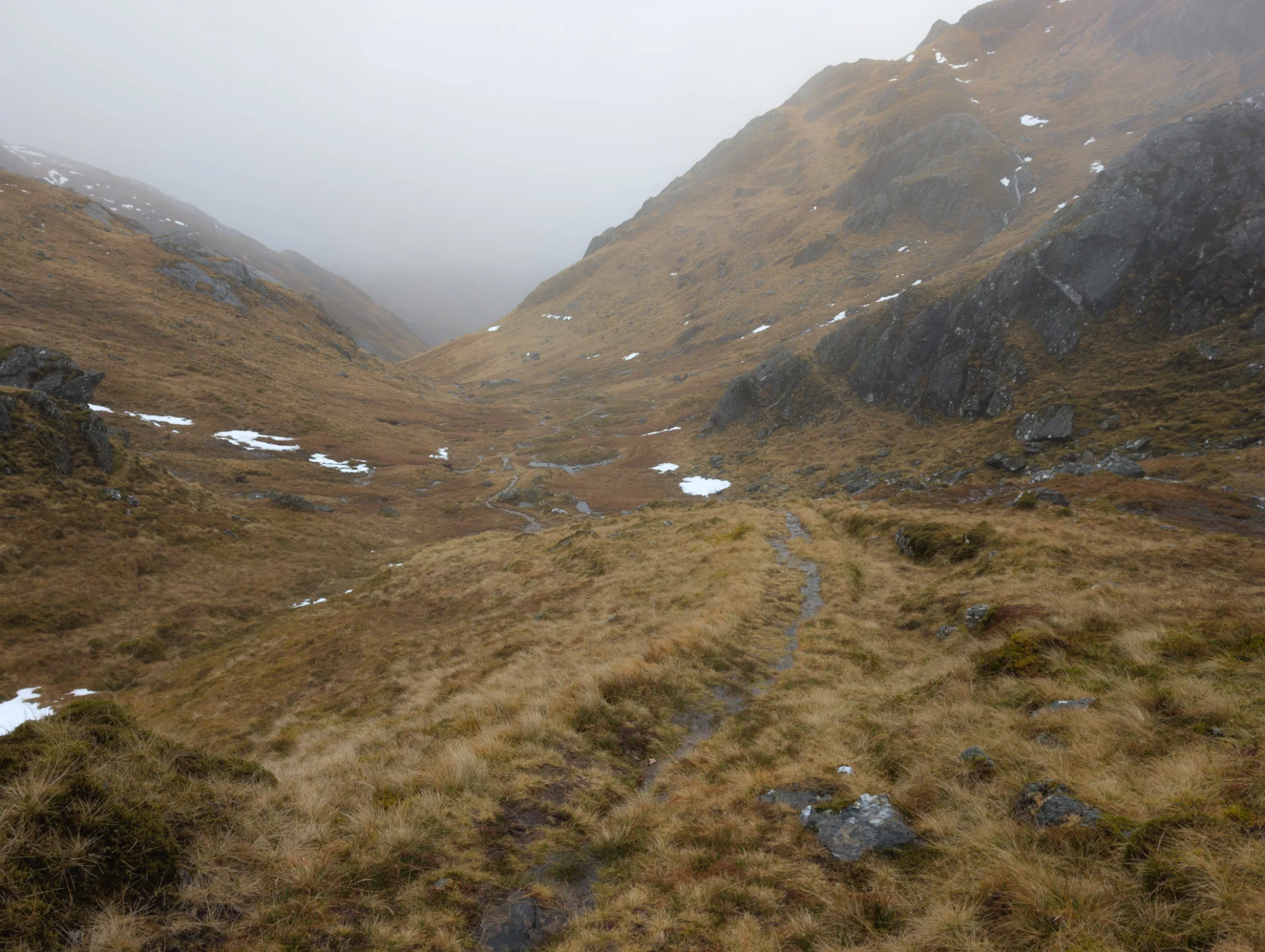 Auf dem Pass — Schnee in den Senken, sonst nur Heide und Stein
