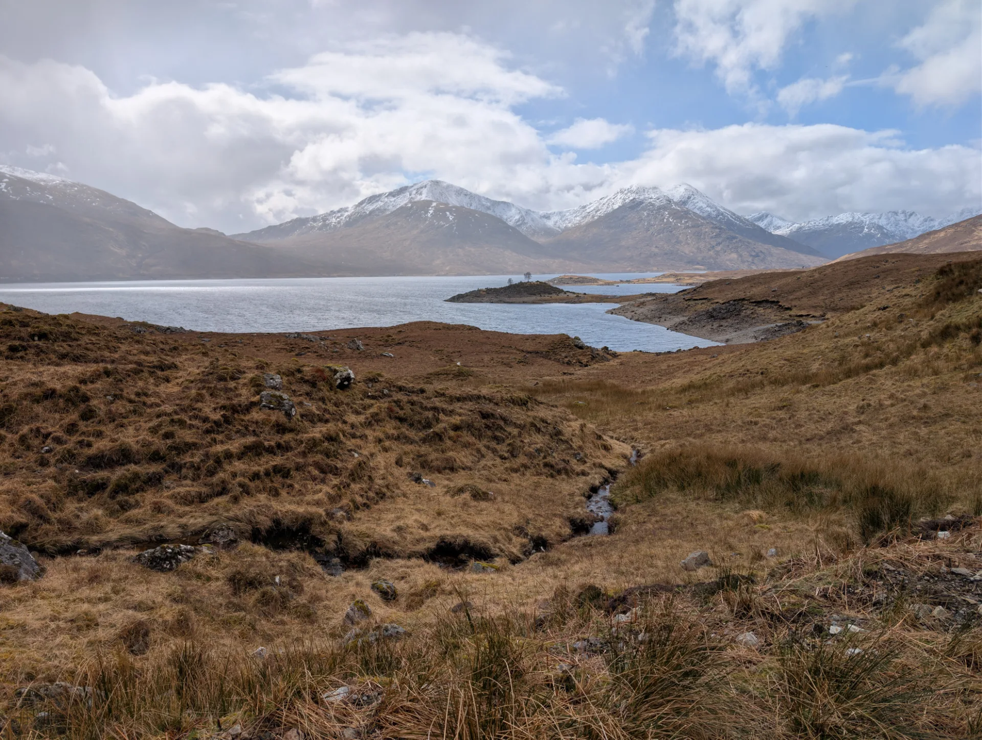 Loch mit kleiner Insel im Spätsonnenlicht