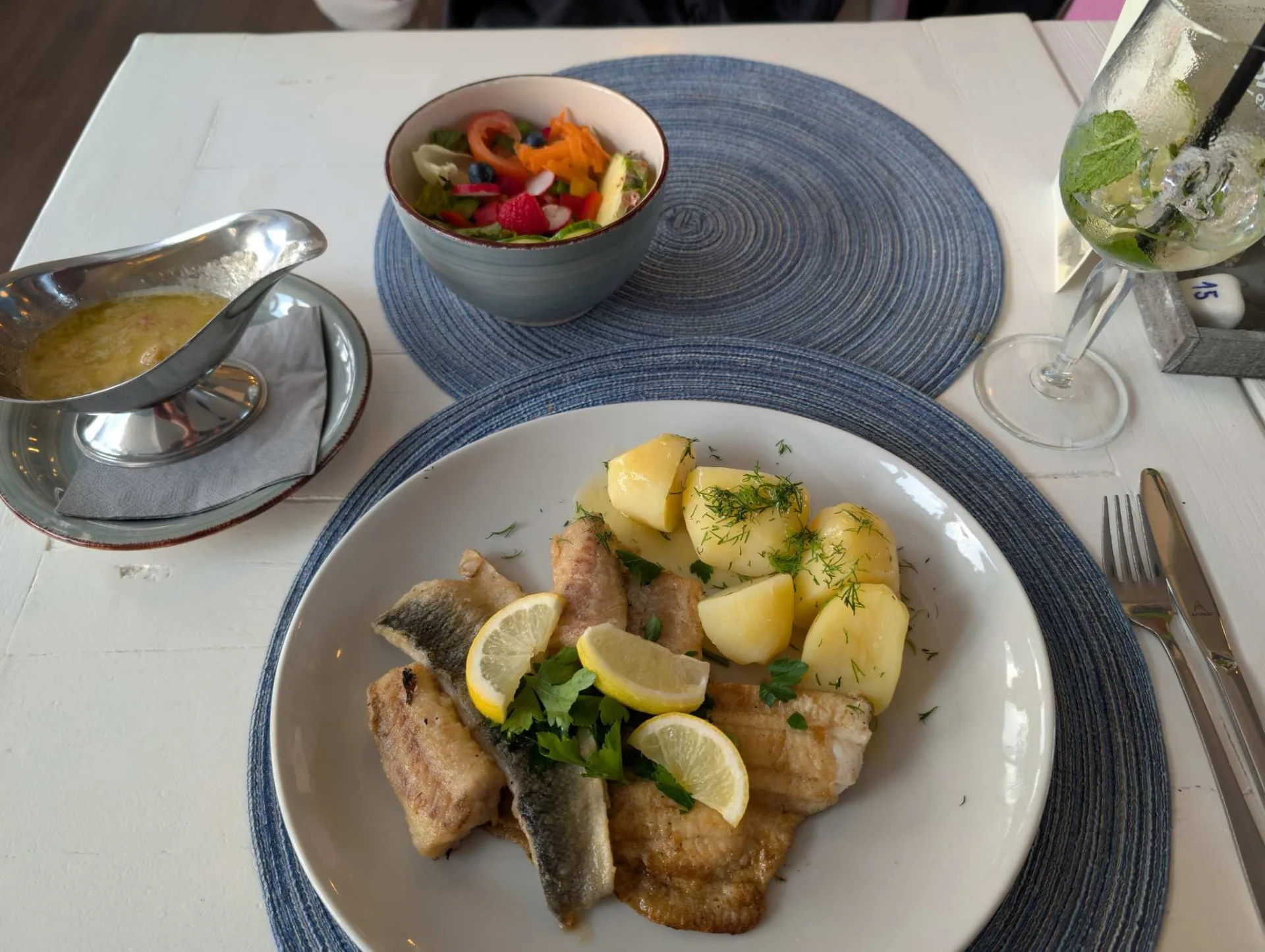 Inselküche: gebratener Fisch mit Salzkartoffeln, Dill und Zitrone, dazu Salat und zerlassene Butter.