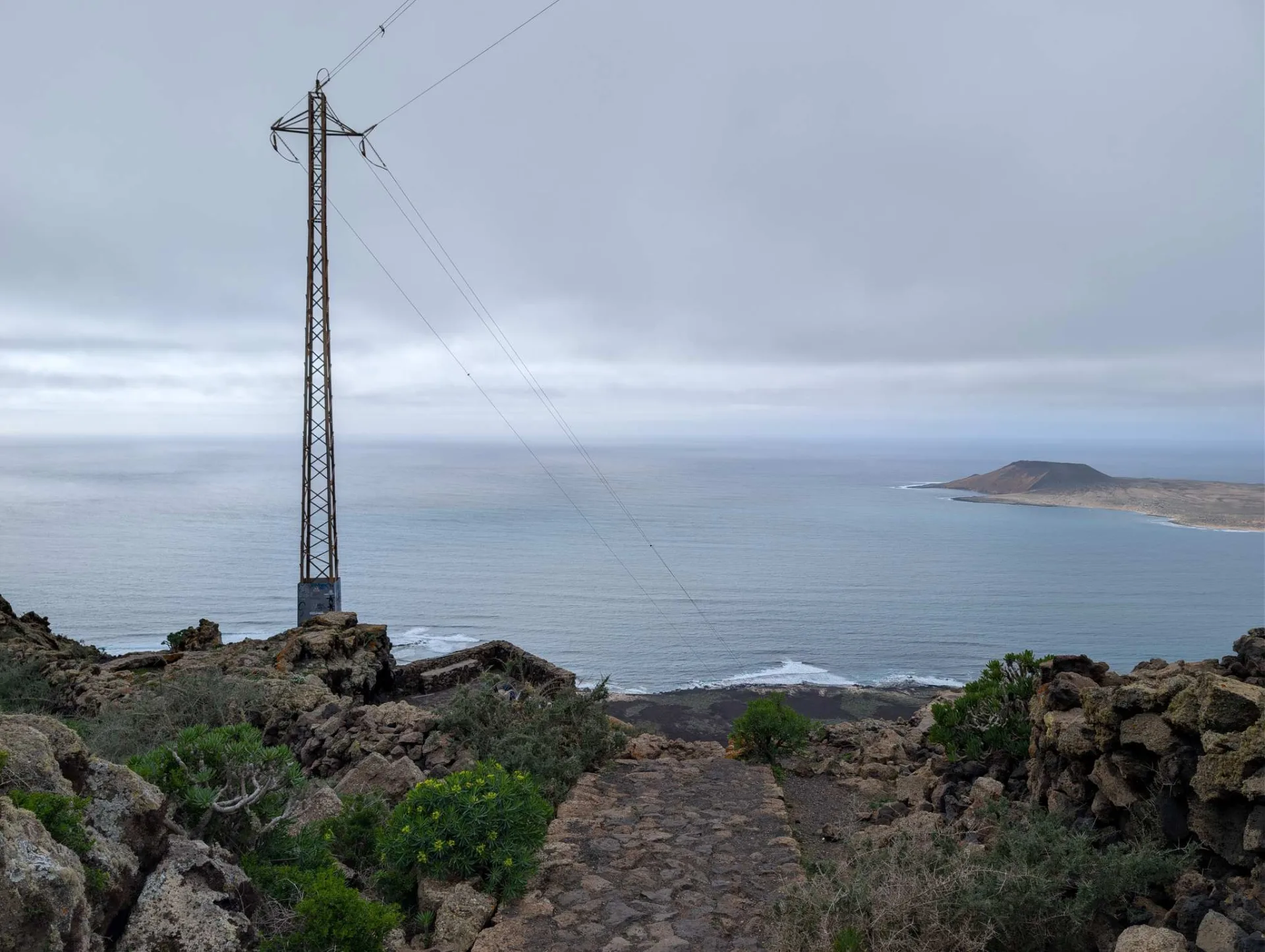 Vom Klippenrand des Risco de Famara hinüber nach La Graciosa; im Vordergrund ein Strommast.