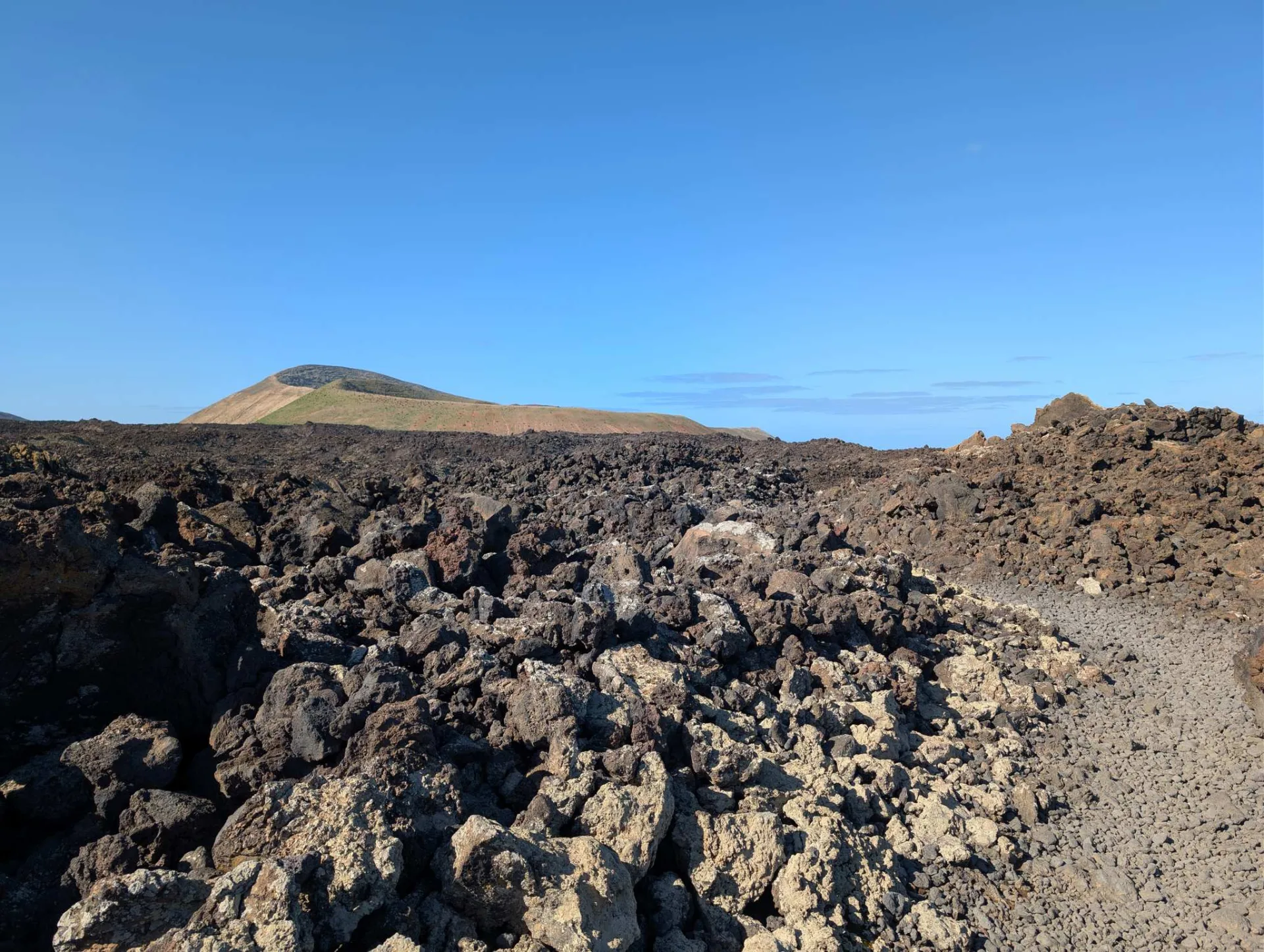 Ein Pfad quert das Lavafeld, ringsum die Vulkankegel.