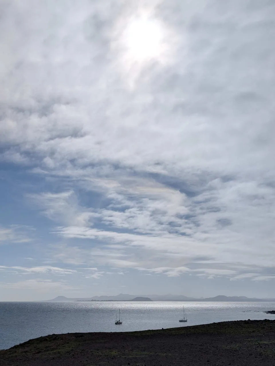 Ein weiter, fast menschenleerer Sandstrand unter bedecktem Himmel.