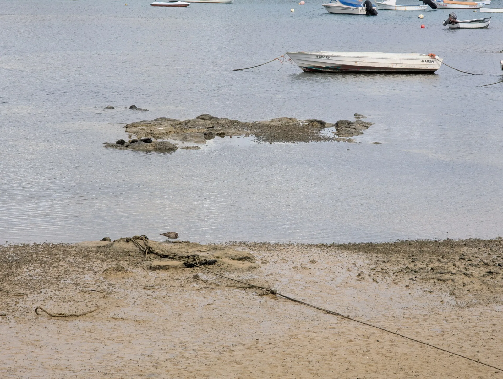 Bei Ebbe liegen kleine Boote auf den Felsen der Lagune.