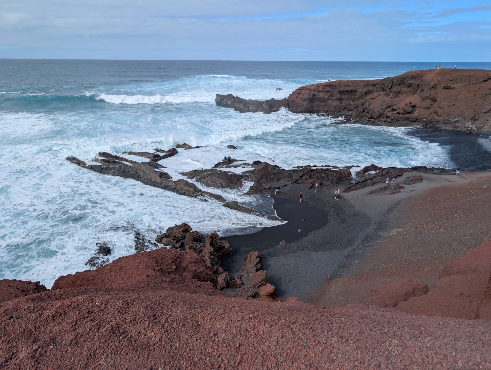 Rote Tuffklippen und Brandung an der Küste von El Golfo.