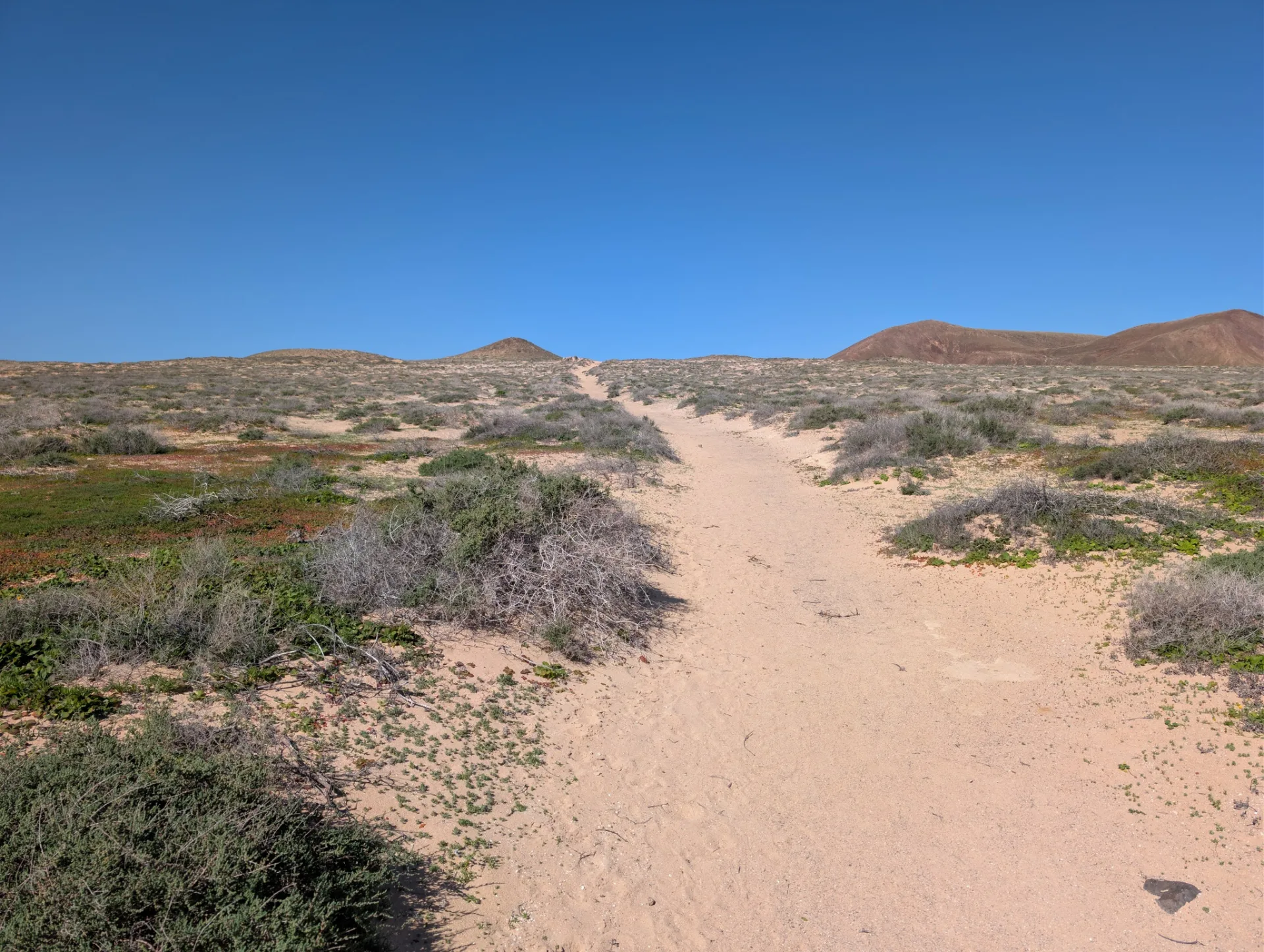 Eine Sandpiste quert La Graciosa unter weitem Himmel.