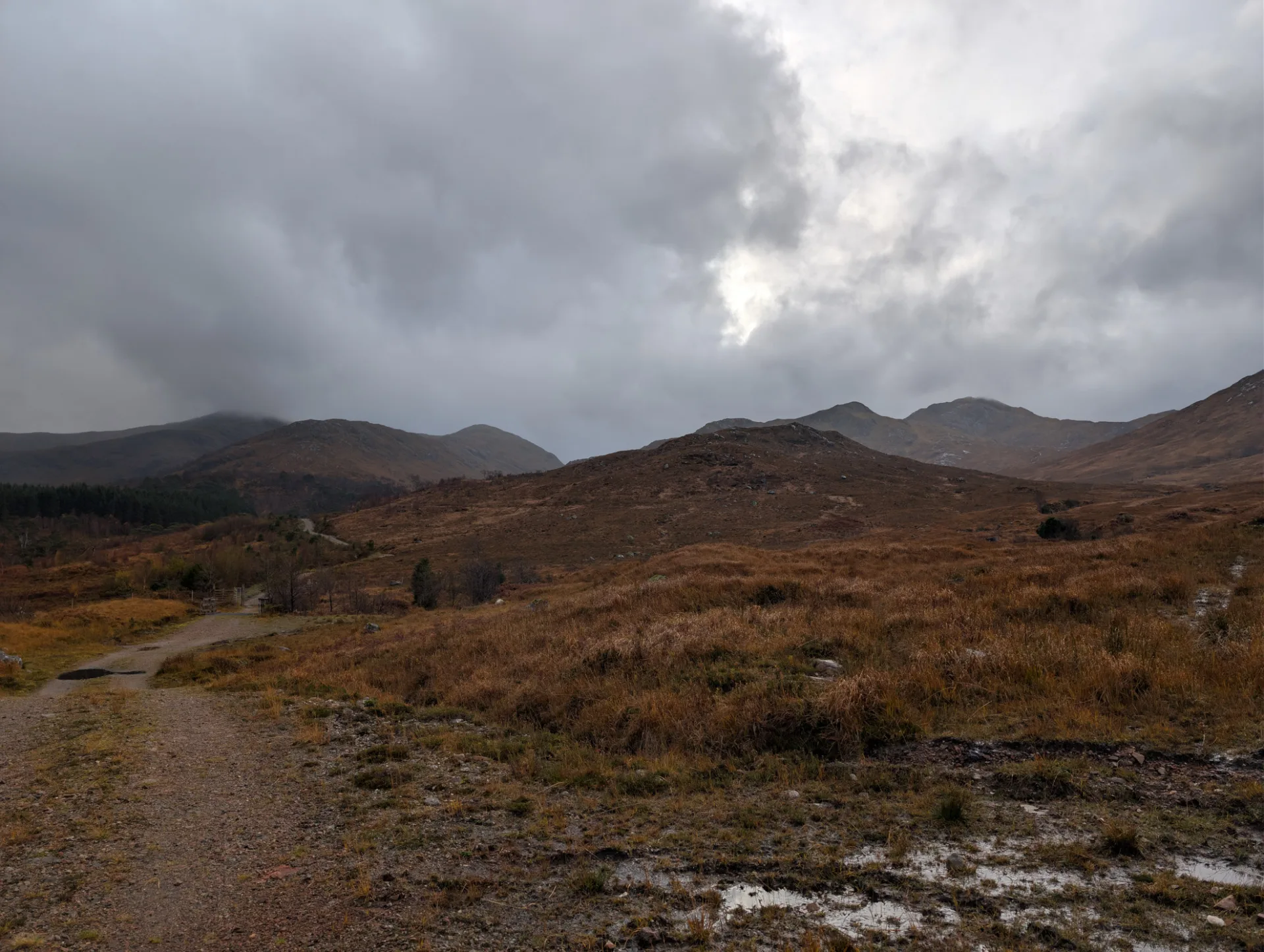 Hochlandweg unter dramatischen Wolken — kurzer Lichtdurchbruch über den Graten