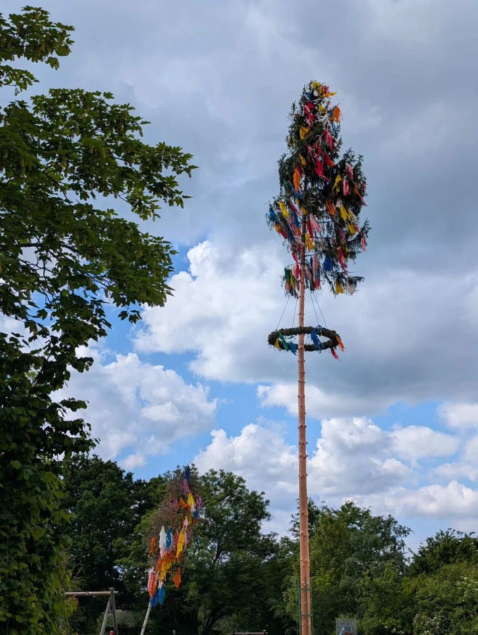 Ein geschmückter Maibaum in einem Dorf am Weg.